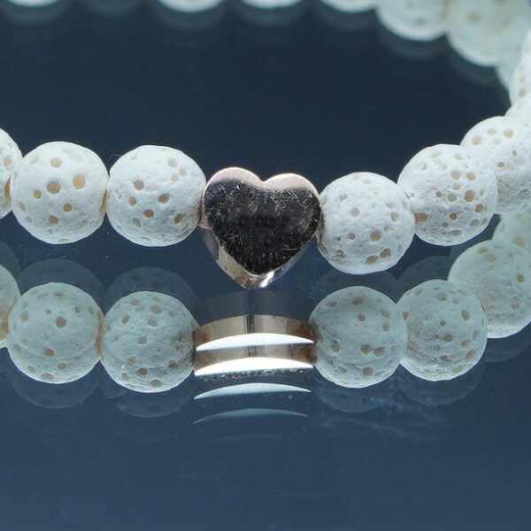 Bracelet en pierre de lave 6 mm blanches avec coeur doré, taille 180 mm. Élégant et pratique, il utilise l'aromathérapie pour une protection anti-moustiques naturelle.
