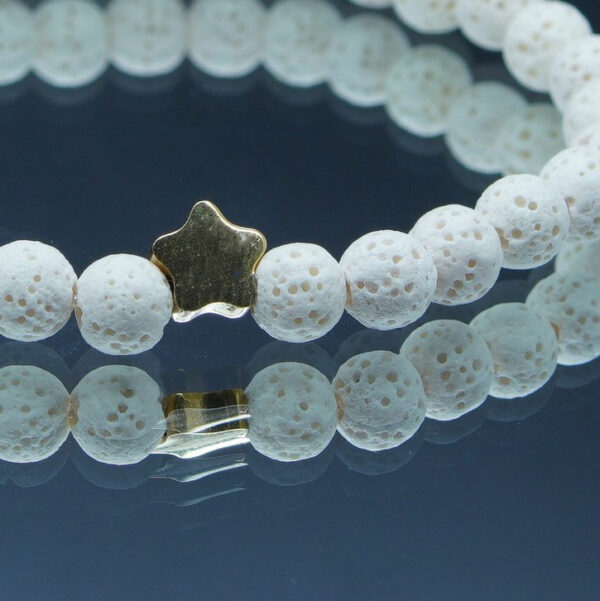 Bracelet en pierre de lave 6 mm blanches avec étoile dorée, taille 180 mm. Élégant et pratique, il utilise l'aromathérapie pour une protection anti-moustiques naturelle.
