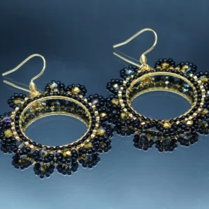 Boucles d'oreilles rondes avec perles de rocaille noires et dorées, tissées à la main autour d'un anneau doré. Design raffiné et élégant, parfait pour sublimer un look avec une touche de sophistication.