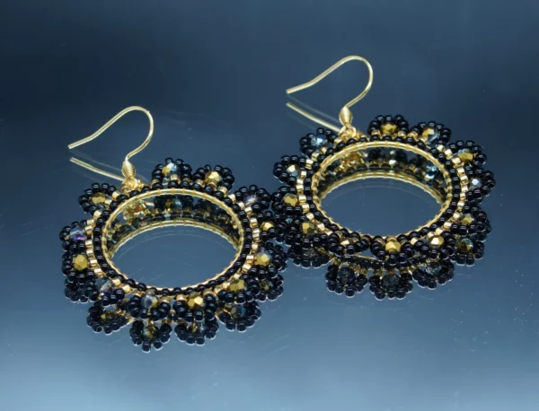 Boucles d'oreilles rondes avec perles de rocaille noires et dorées, tissées à la main autour d'un anneau doré. Design raffiné et élégant, parfait pour sublimer un look avec une touche de sophistication.