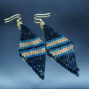 Boucles d'oreilles pendantes en perles de rocaille tissées à la main, dans des tons bleus, dorés et bleus foncés. Élégantes et géométriques, elles ajoutent une touche unique et sophistiquée à toute tenue.