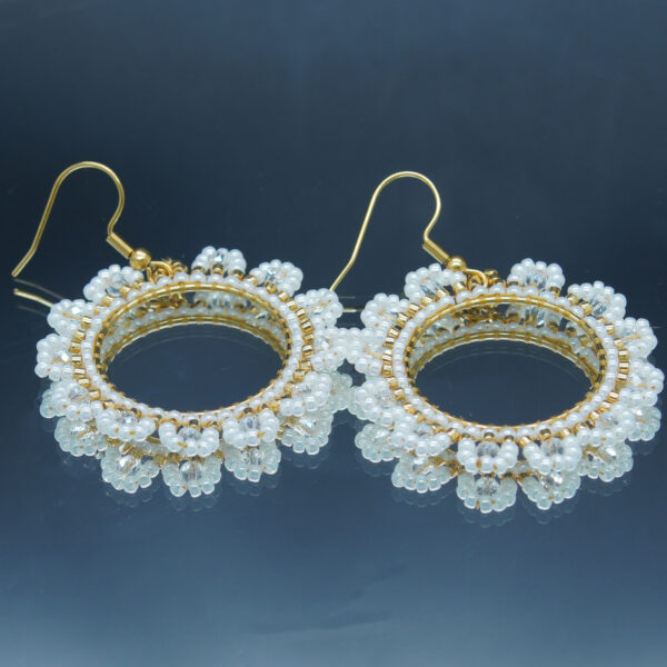 Boucles d'oreilles rondes avec perles de rocaille blanches et dorées, tissées à la main autour d'un anneau doré. Design raffiné et élégant, parfait pour sublimer un look avec une touche de sophistication.