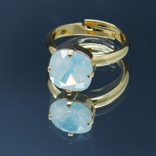 Bague dorée ajustable avec crystal bleu opale de haute qualité 10 x 10 mm. Élégante et intemporelle, elle offre un éclat raffiné et un confort sur mesure.