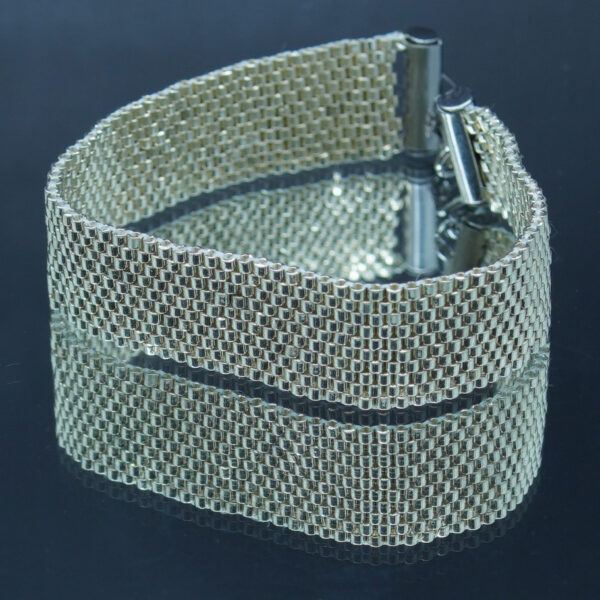 Bracelet tissé à la main en perles Miyuki Delica argentées sur 10 rangs avec fermoir et finitions en acier inoxydable. Un bijou raffiné et intemporel, parfait pour une touche d’élégance au quotidien.