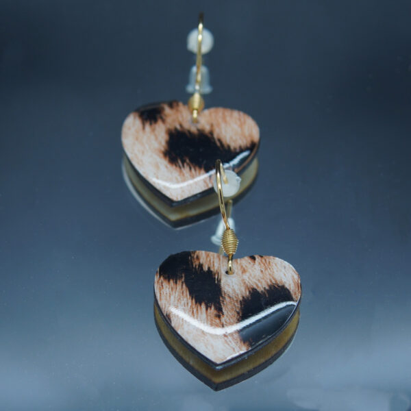 Paire de boucles d’oreilles en forme de cœur, réalisées en bois finement découpé avec un motif animalier comme décoration. Chaque fleur est ornée d’un strass bleu turquoise scintillant en son centre, ajoutant une touche lumineuse et élégante. Montées sur des attaches en acier inoxydable, ces boucles d’oreilles sont légères et confortables à porter.
