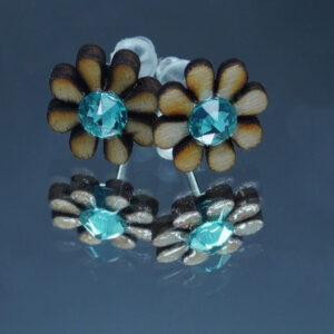 Une paire de boucles d’oreilles en forme de marguerites d'un diamètre de 10 mm, réalisées en bois finement découpé avec des pétales délicatement définis. Chaque fleur est ornée d’un strass bleu clair scintillant en son centre, ajoutant une touche lumineuse et élégante. Montées sur des attaches en acier inoxydable, ces boucles d’oreilles sont légères et confortables à porter.