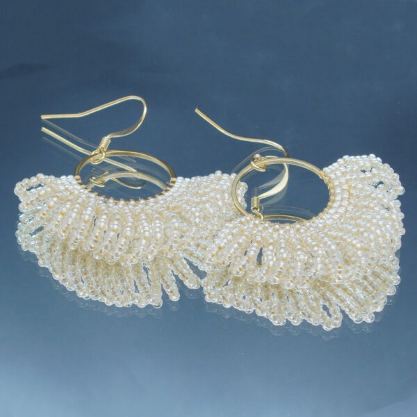 Boucles d'oreilles dorées en perles beiges tressées à la main, en forme d'éventail. Un bijou raffiné et lumineux au design élégant et sophistiqué.