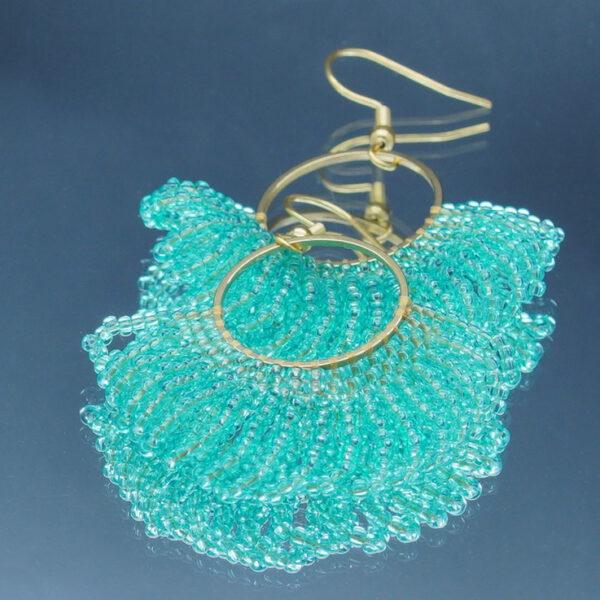 Boucles d'oreilles dorées en perles vert d'eau tressées à la main, en forme d'éventail. Un bijou raffiné et lumineux au design élégant et sophistiqué.