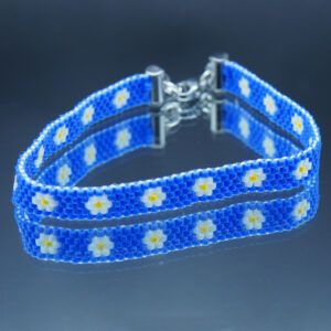 Bracelet tissé en perles Miyuki bleu cobalt, avec un motif géométrique de marguerite. Encadré de chaînettes dorées et doté d’un fermoir ajustable, il allie élégance et finesse pour un style sophistiqué et intemporel.