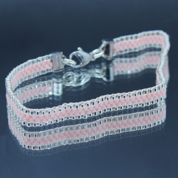 Bracelet tissé à la main sur 4 rangs avec perles Miyuki argentées et rose pâle, et finitions en acier inoxydable doré. Un bijou élégant et raffiné, au design fin et lumineux.