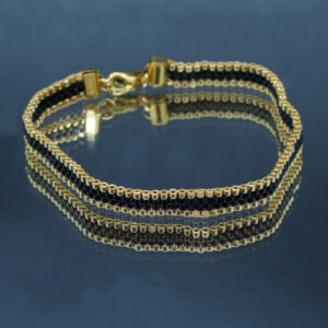 Bracelet tissé à la main sur 4 rangs avec perles Miyuki dorées et noires, et finitions en acier inoxydable doré. Un bijou élégant et raffiné, au design fin et lumineux.