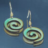 Boucles d'oreilles pendantes effet céramique émaillée, en forme de spirale, avec des nuances de vert et de brun. Les crochets sont en métal doré avec un détail en fil enroulé. Le design artisanal met en valeur des finitions brillantes et un contraste subtil entre les couleurs.