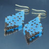 Paire de boucles d’oreilles en forme de losange, tissées à la main avec des perles Cube Miyuki aux nuances de bronze et de bleu, créant un effet scintillant et profond. Les reflets subtils rappellent un ciel étoilé. Montées sur des crochets dorés en acier inoxydable avec embouts en silicone, ces boucles sont légères et confortables à porter.