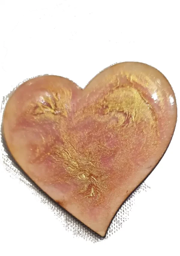 Broche artisanale en forme de cœur et en bois gravé, décorée de rouge avec des reflets d'or.