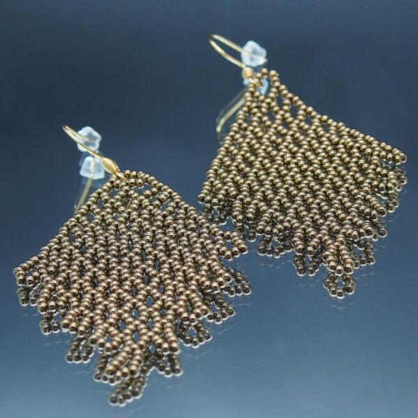 Boucles d'oreilles pendantes en dentelles de perles bronze, formant un motif délicatement tissé. Montées sur des crochets dorés, elles offrent un effet fluide et scintillant, parfait pour une touche d’élégance et de raffinement.