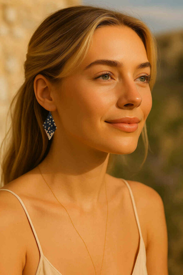 Modèle portant les boucles d’oreilles en forme de losange, tissées à la main avec des perles Cube Miyuki aux nuances de noir et d'or, créant un effet scintillant et profond. Les reflets subtils rappellent un ciel étoilé. Montées sur des crochets dorés en acier inoxydable avec embouts en silicone, ces boucles sont légères et confortables à porter.