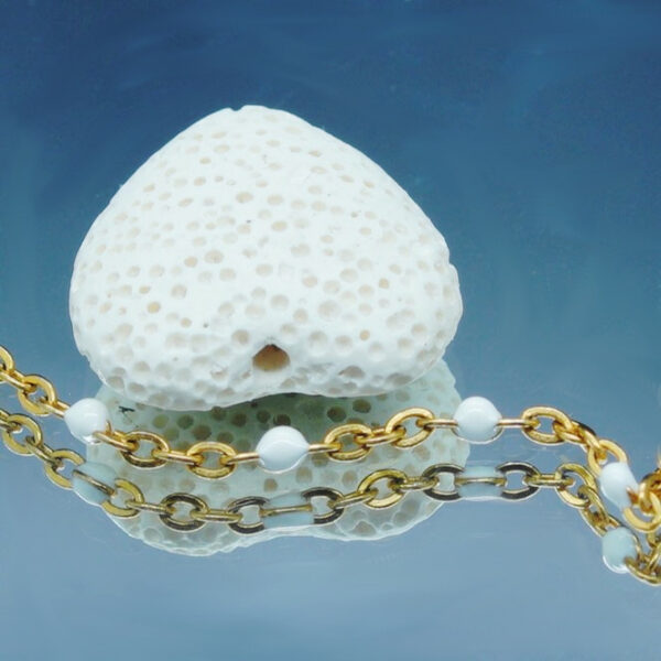 Chaîne de cheville dorée avec perles blanches et cœur en pierre de lave poreuse, idéale pour diffuser des huiles essentielles anti-moustiques avec élégance.