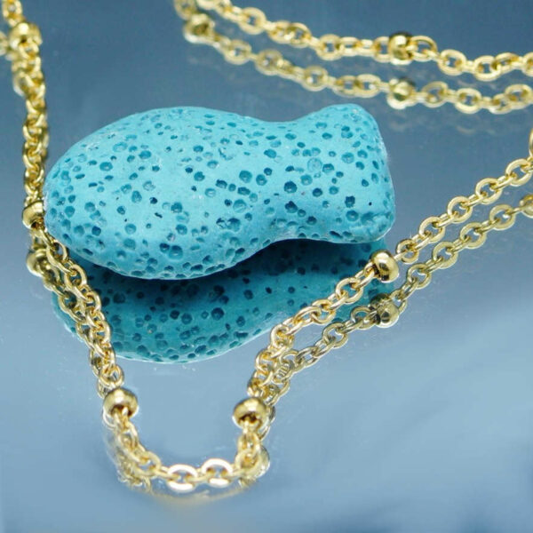 Chaîne de cheville dorée avec perles blanches et poisson en pierre de lave poreuse, idéale pour diffuser des huiles essentielles anti-moustiques avec élégance.